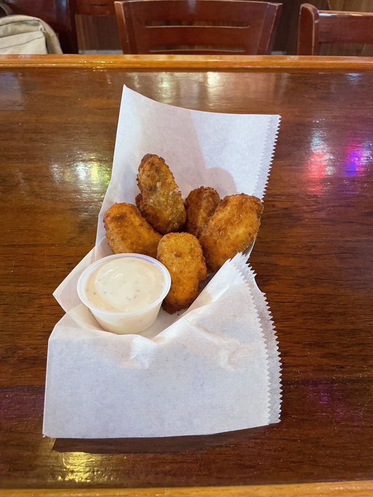 Breaded jalapeño cream cheese poppers in a paper-lined basket with a cup of homemade ranch.