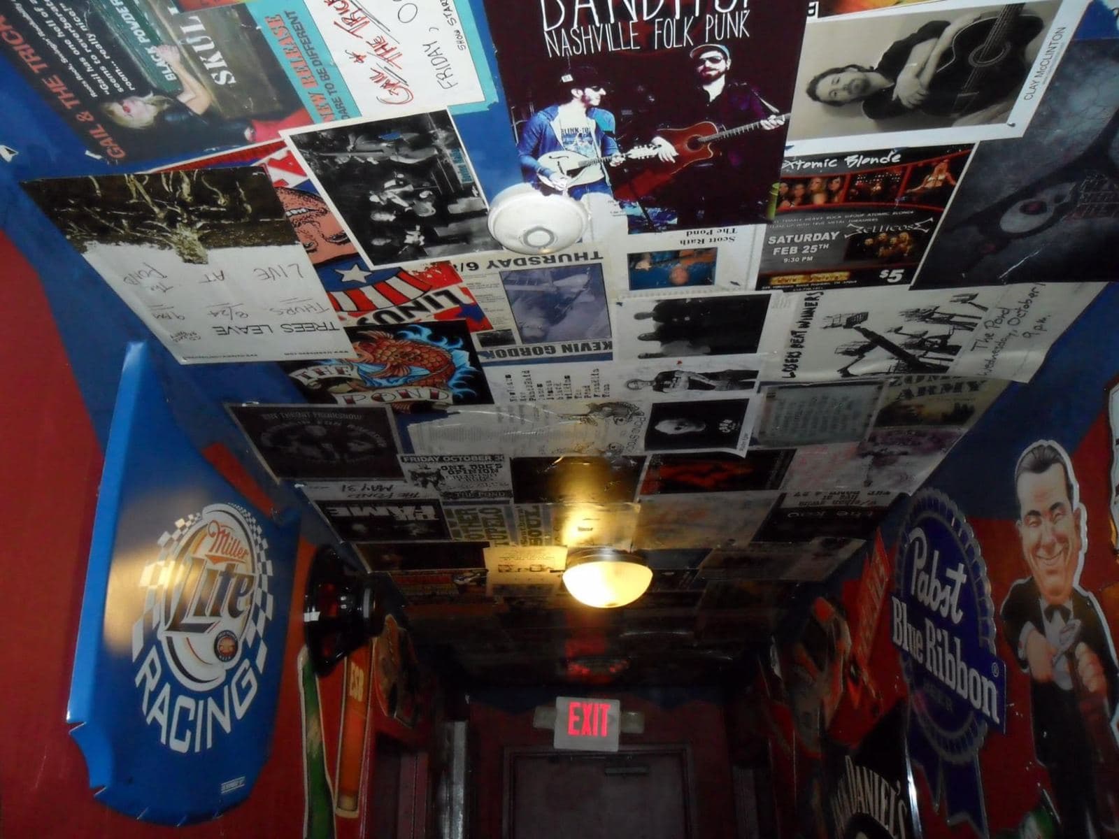 The ceiling over the back hallway papered edge to edge with stapled gig posters and handbills from past shows, beer signs on the walls below.